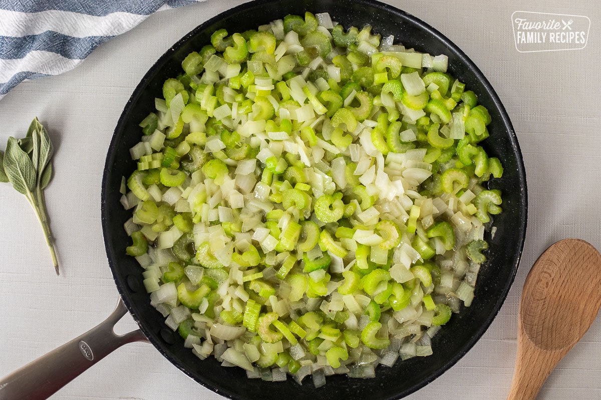 Skillet with diced celery and onion. Wooden spoon on the side.