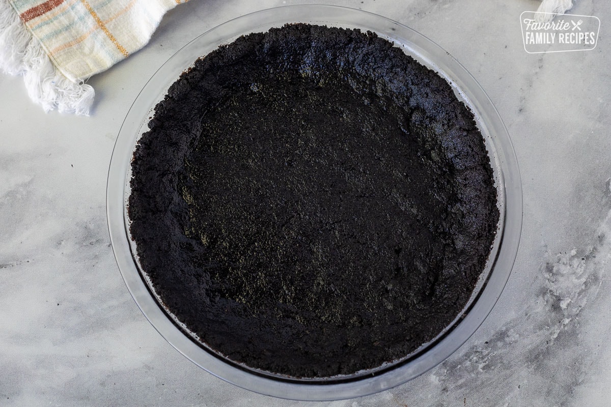 Pressed Oreo crust mixture in a glass pie dish for Chocolate Satin Pie.