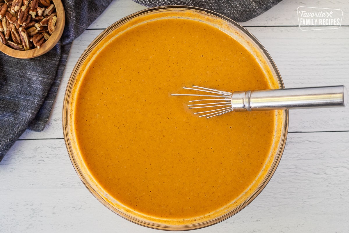 Glass bowl with pumpkin mixture and whisk.