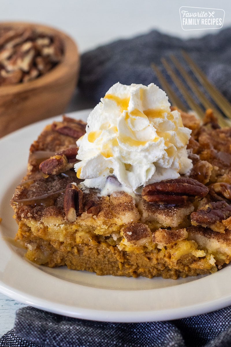 Slice of Pumpkin Cobbler with whipped cream and caramel drizzle on a plate.