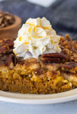 Slice of Pumpkin Cobbler with whipped cream and caramel drizzle on a plate.