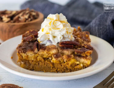 Slice of Pumpkin Cobbler with whipped cream and caramel drizzle on a plate.