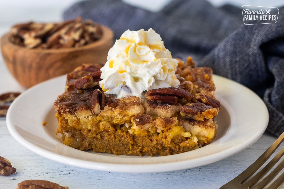 Slice of Pumpkin Cobbler with whipped cream and caramel drizzle on a plate.