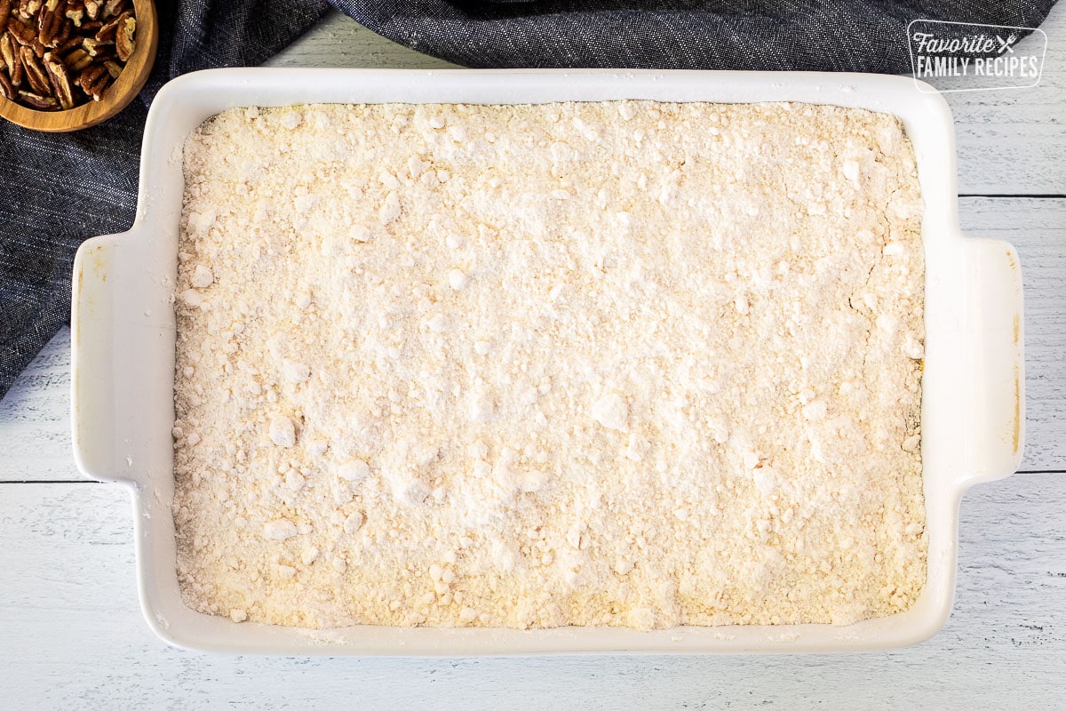 Baking dish with cake mixture over pumpkin.