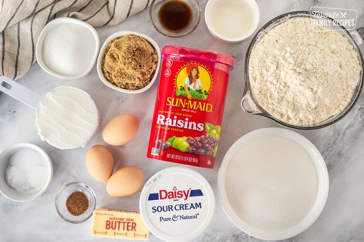 Ingredients to make Raisin Filled Cookies including flour, sugar, sour cream, butter, nutmeg, eggs, shortening, salt, baking powder, baking soda, brown sugar, lemon juice, vanilla and raisins.