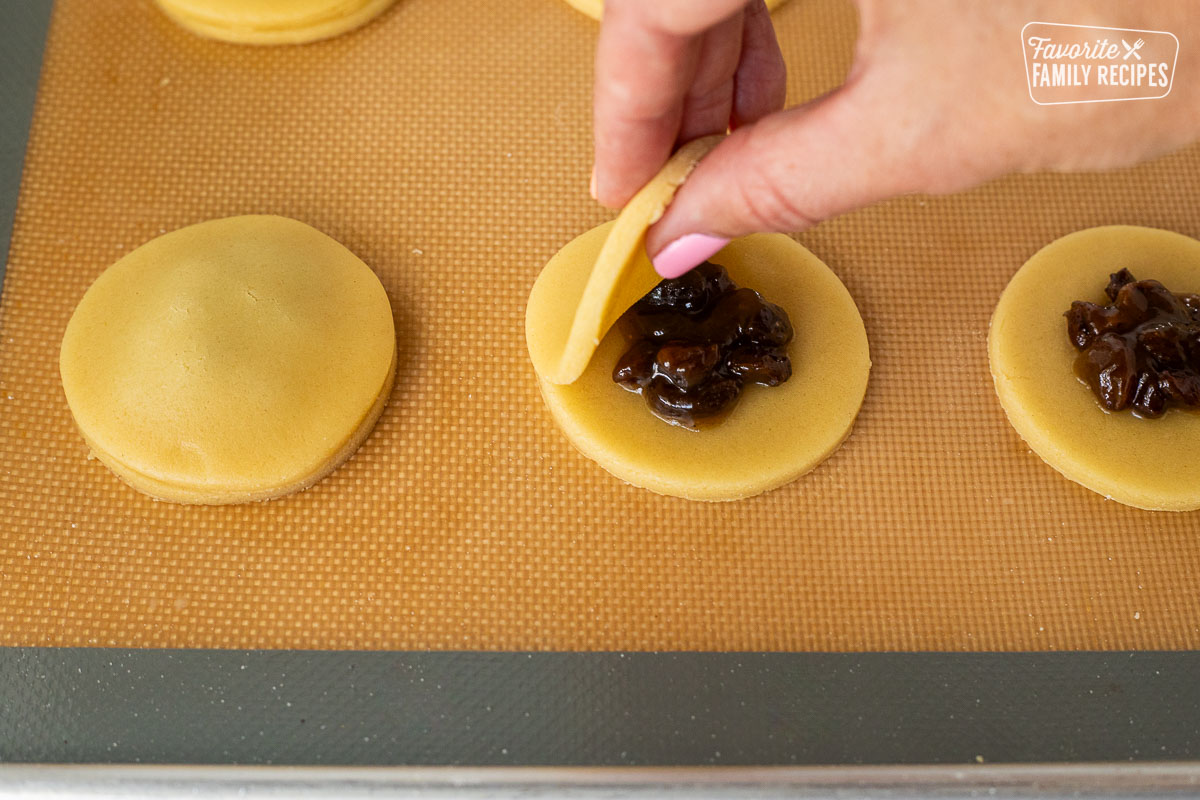 Placing round cookie dough on top of raisin.