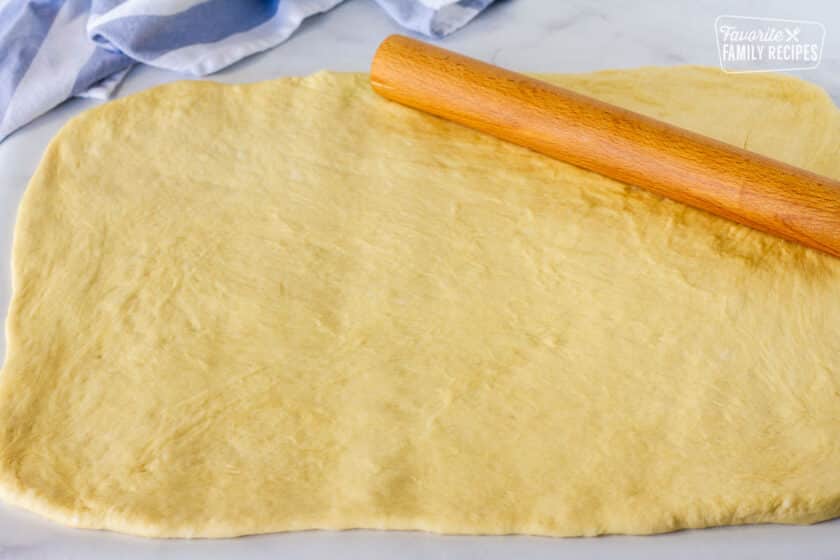 Rolled out dough with a wooden rolling pin.