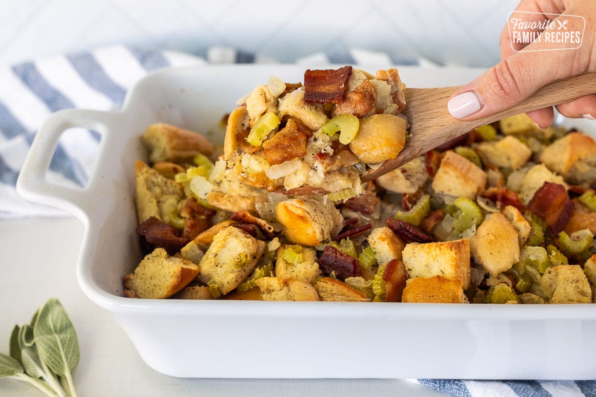 Hand holding a wooden spoon with scoop on Bacon Stuffing.