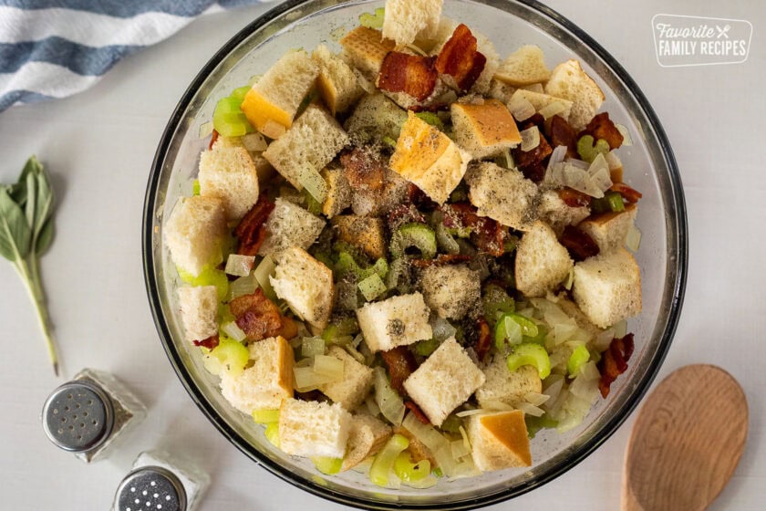 Seasoning on top of mixing bowl of bread, celery, onion and bacon.