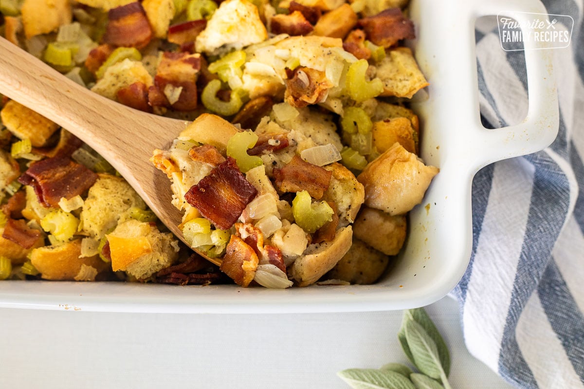 Wooden spoon resting in a casserole dish of Bacon Stuffing.