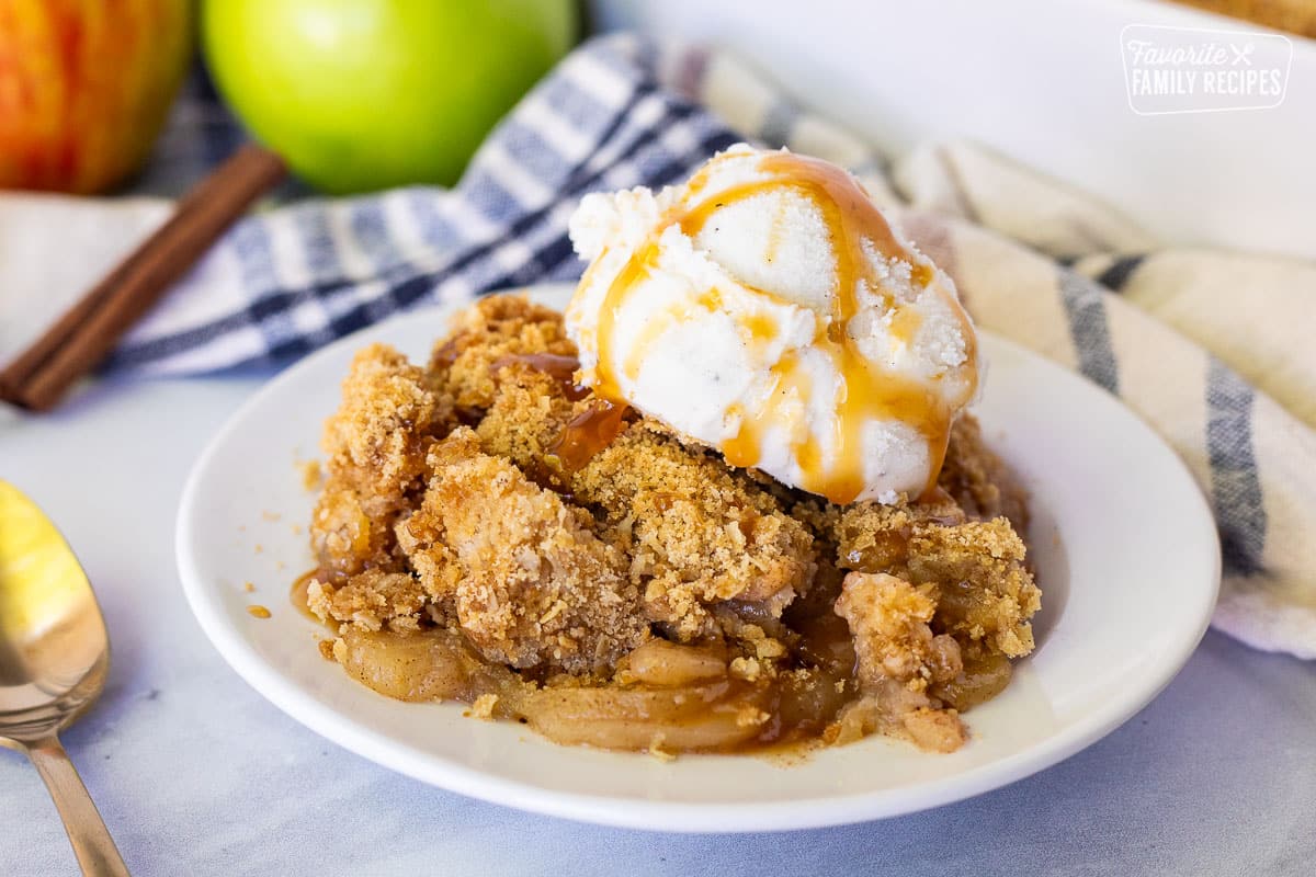 Piece of Apple Crisp on a plate with vanilla ice cream and caramel sauce.