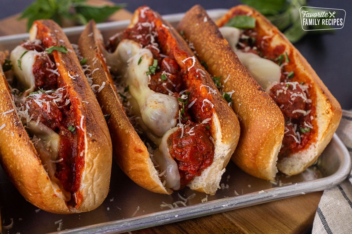 Three Meatball Sandwiches with melted cheese on a toasted roll.