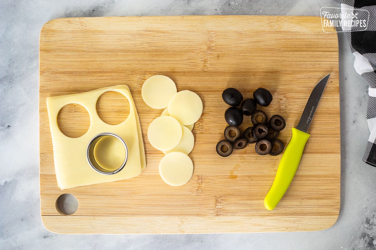 Cut black olives and circle cutter cutting out circle mozzarella cheese.