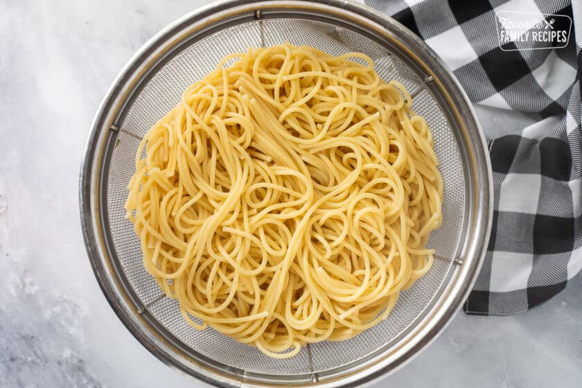 Colander with cooked spaghetti noodles.