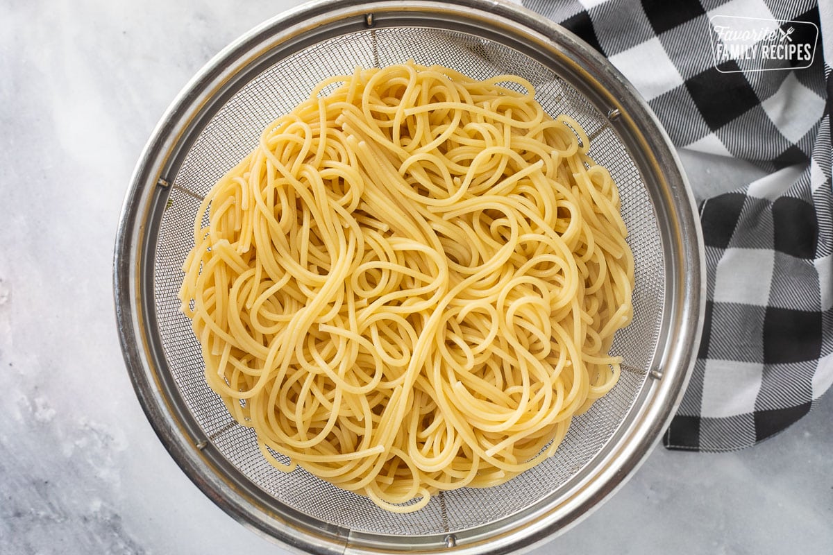 Colander with cooked spaghetti noodles.