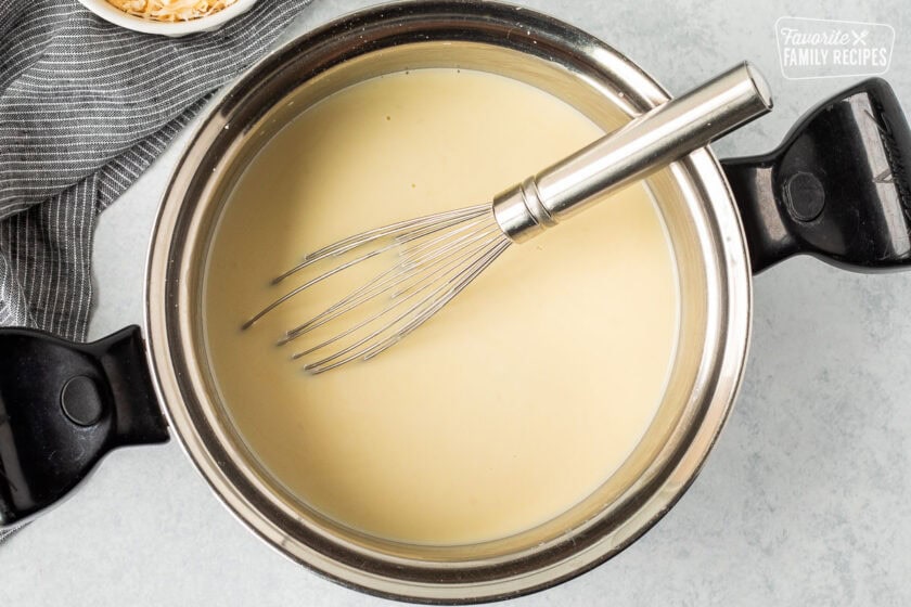 Sauce pan with creamy liquid and whisk.