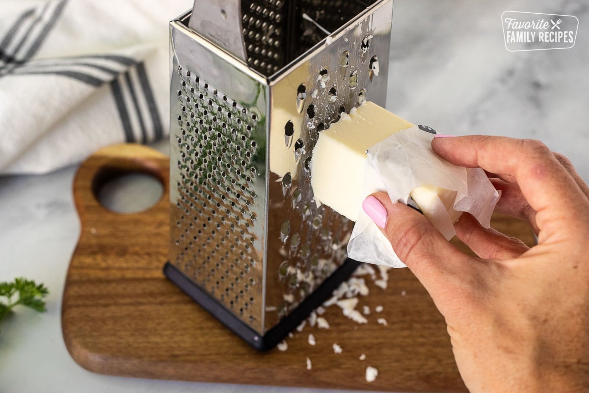 Grating a frozen cube of butter on a cutting board.