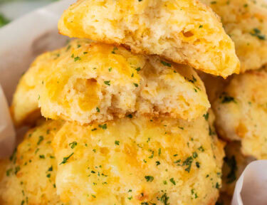 Basket of Cheddar Bay Biscuits with one cut in half.