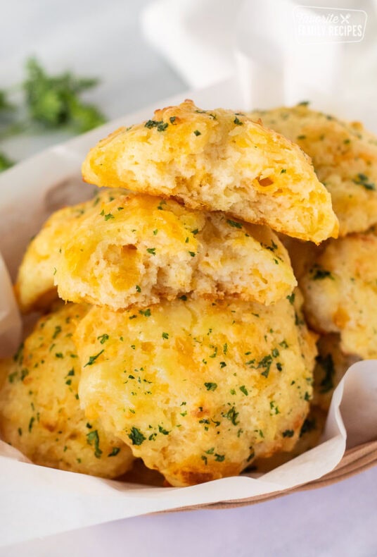 Basket of Cheddar Bay Biscuits with one cut in half.