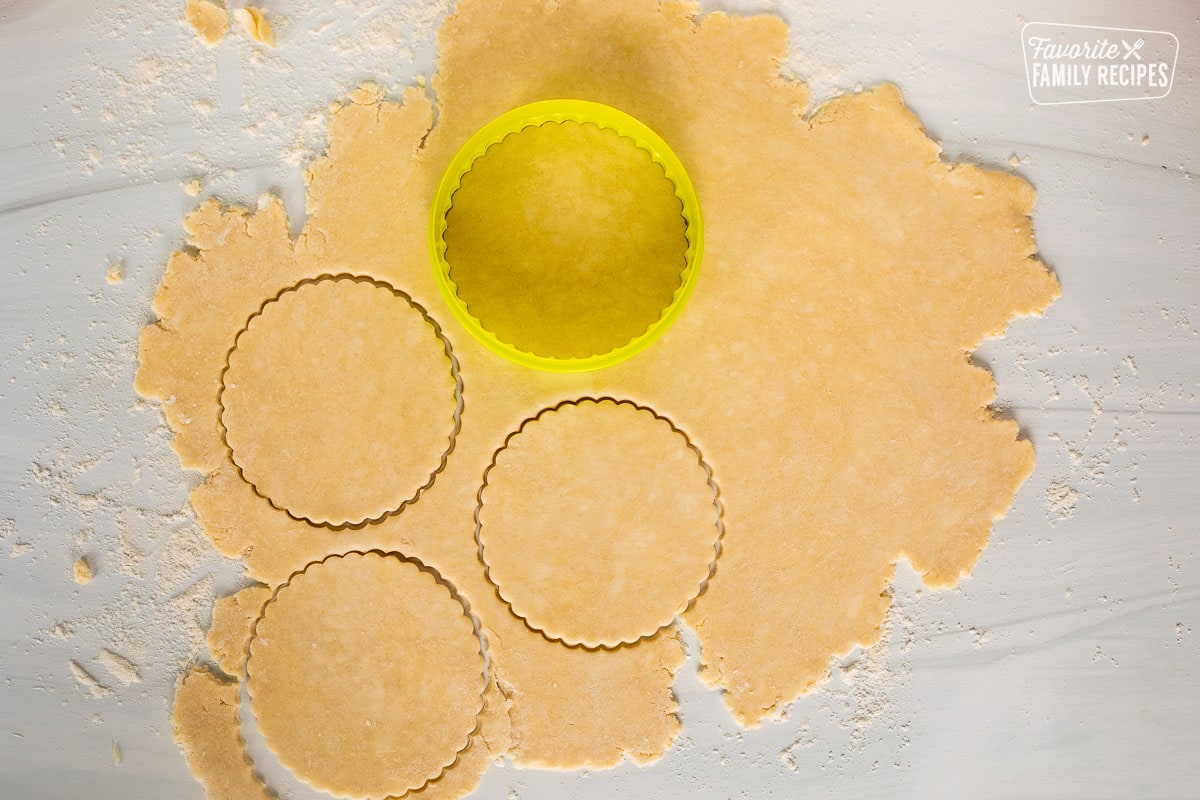 Cutting out pie pastry dough with circle cutter.