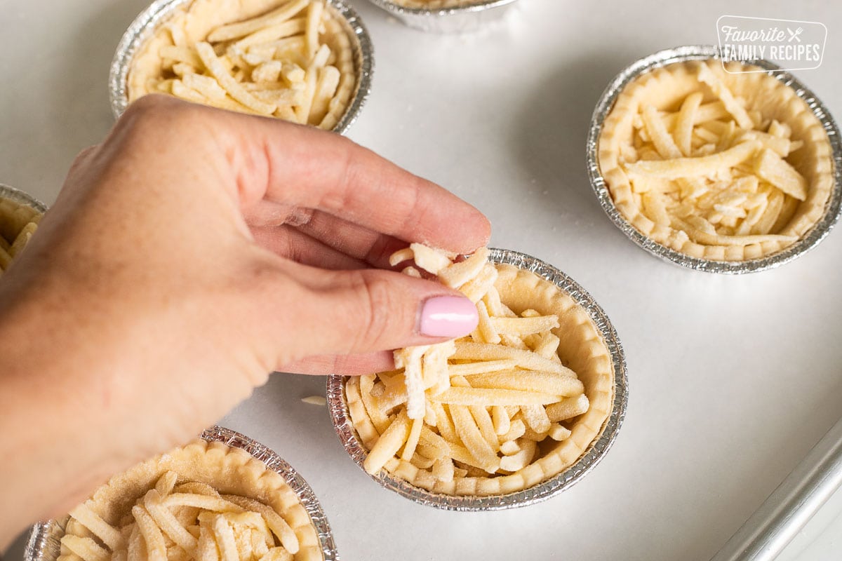 Sprinkling cheese in small pie shells.