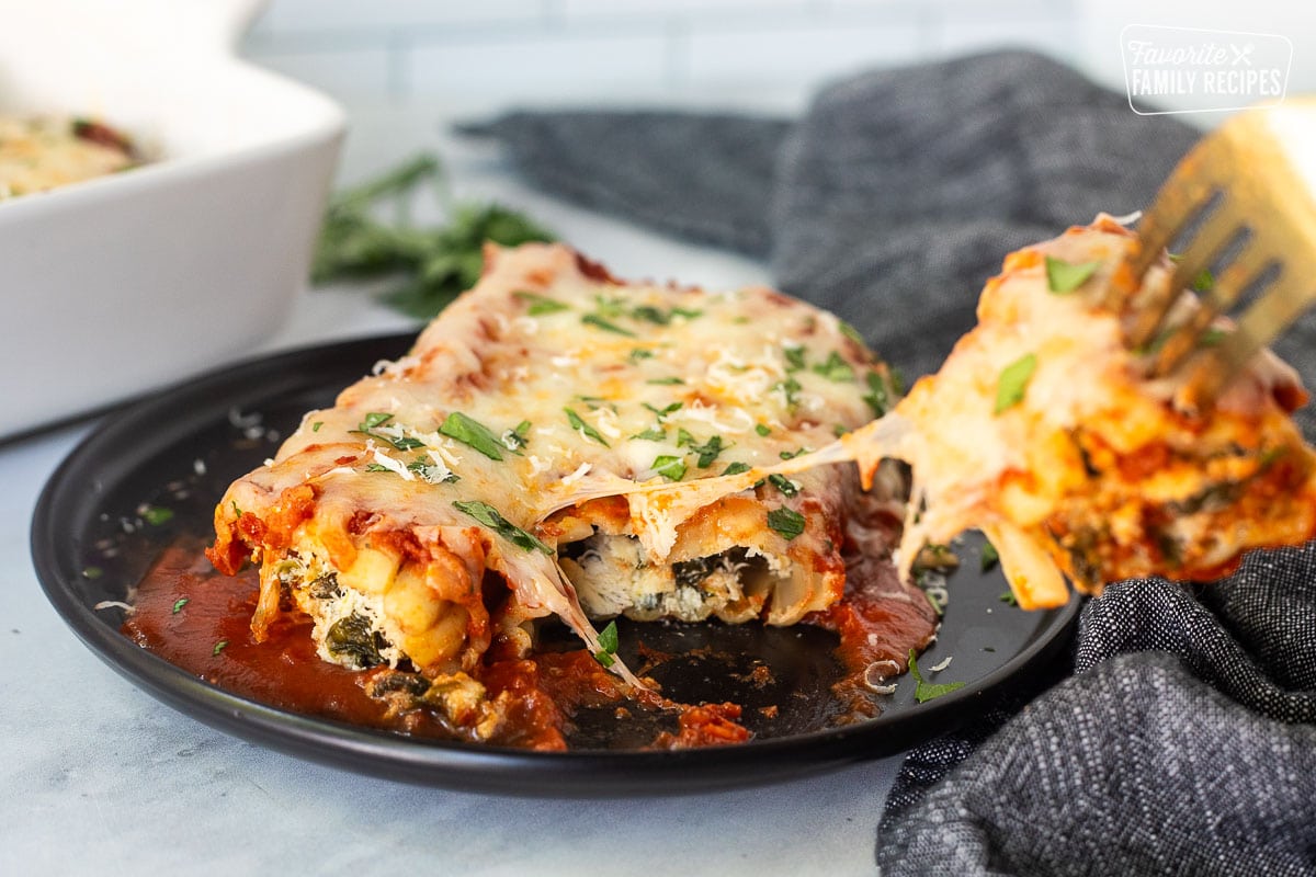 Chicken and Spinach Manicotti on a plate with a fork pulling back a piece.