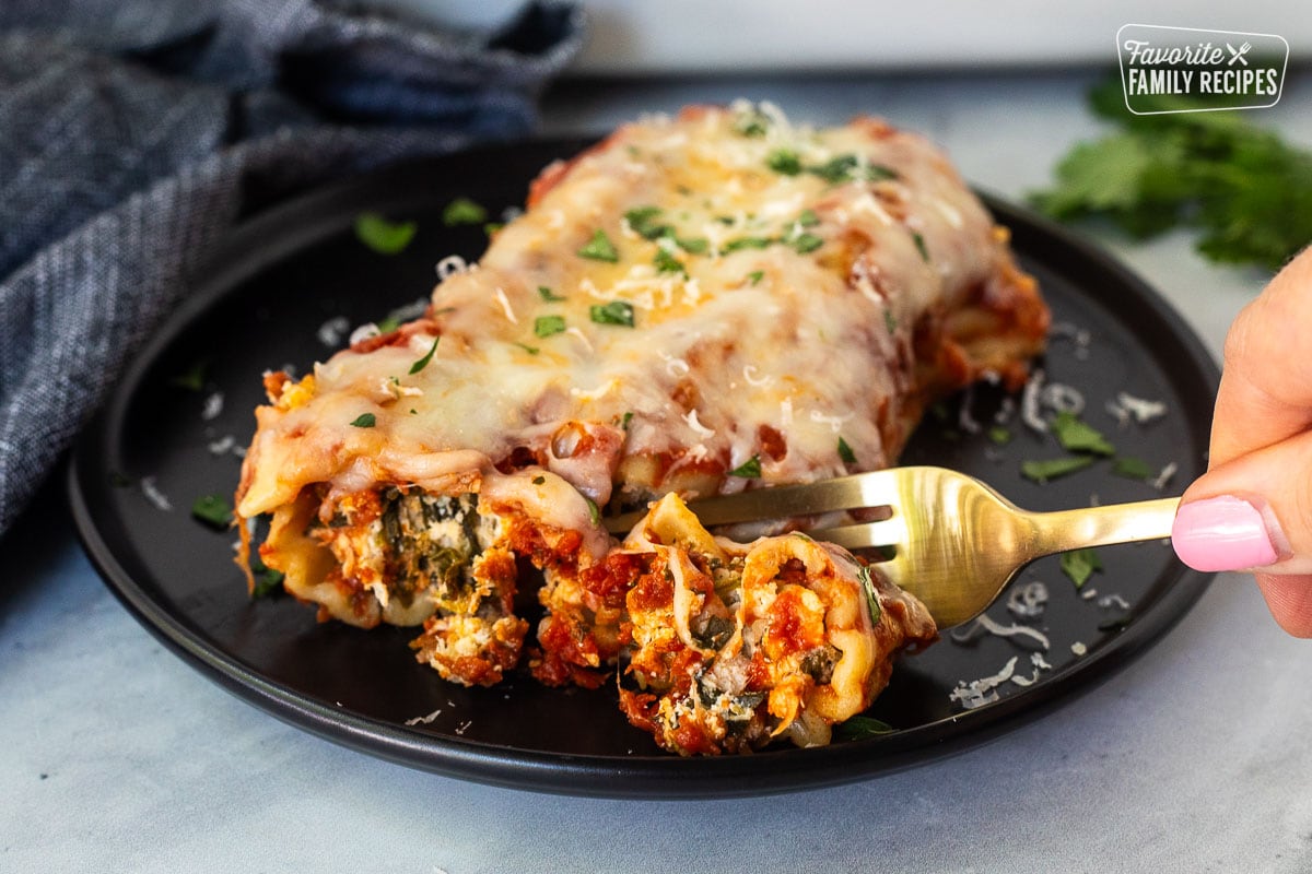 Cutting into a Chicken and Spinach Manicotti shell with a fork.