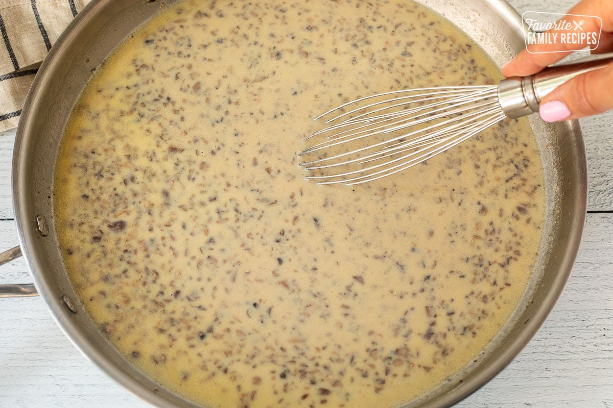 Whisking cream of mushroom condensed soup in skillet.