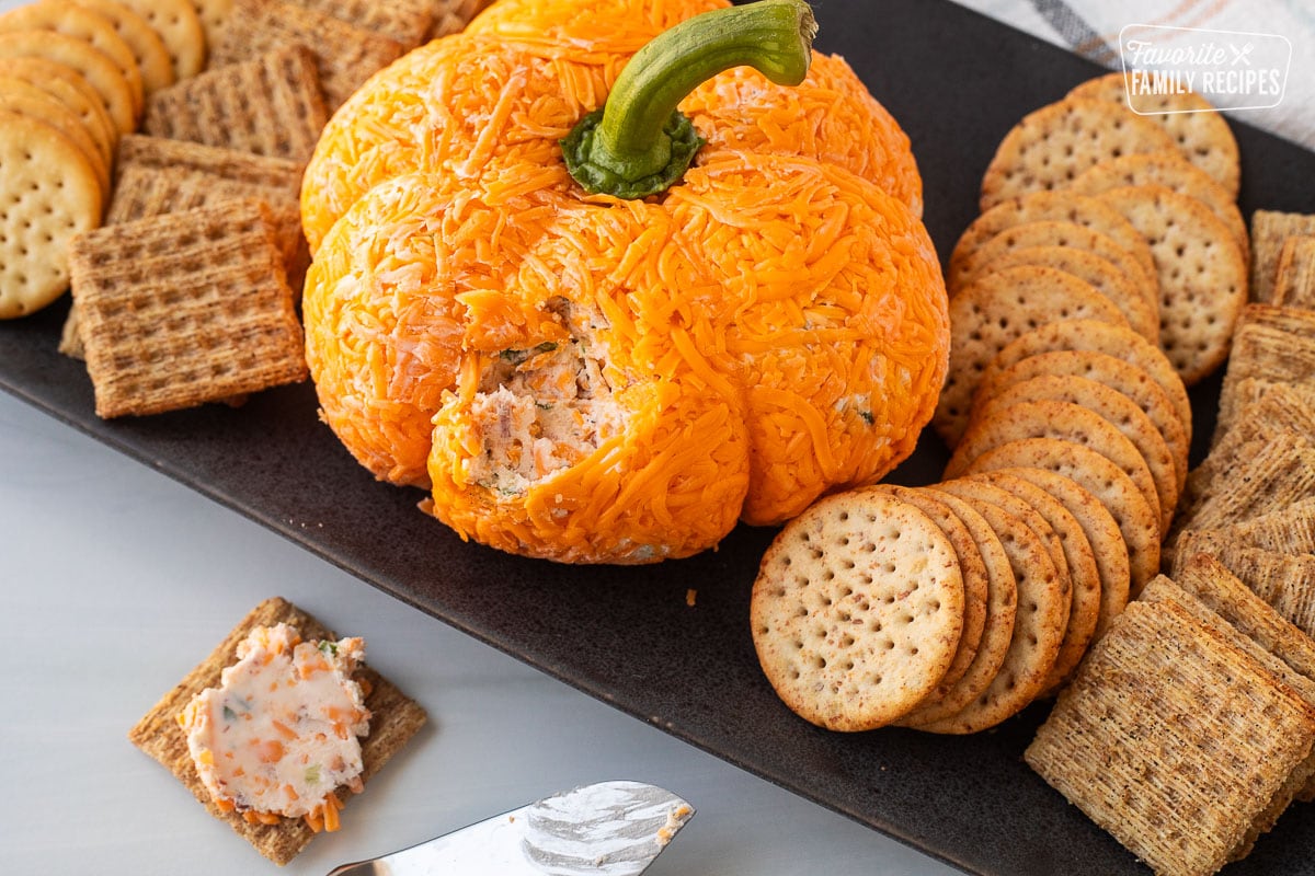 Pumpkin shaped cheese ball spread onto a cracker.