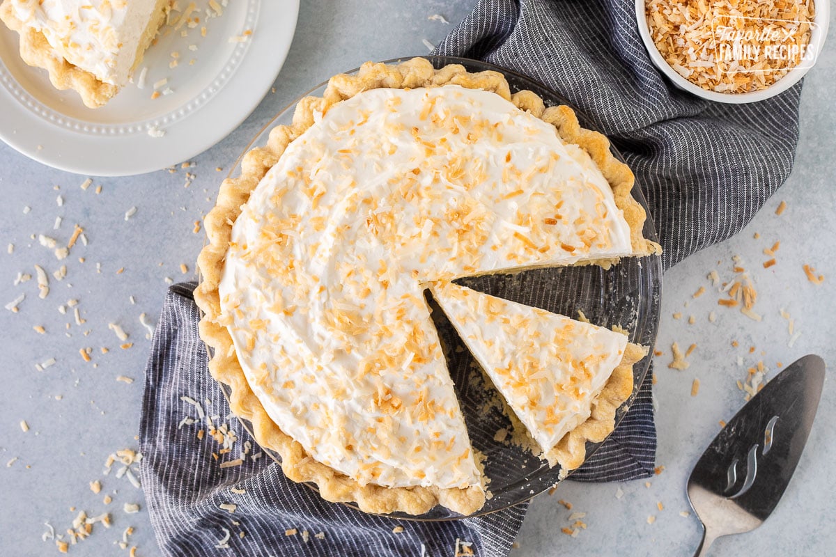 Slice of Coconut Cream Pie in a pie pan with remaining pie.