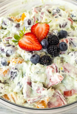 Glass mixing bowl with Easy Fruit Salad topped with strawberry, blackberries and blueberries.