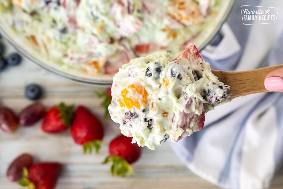 Wooden spoon with scoop of Easy Fruit Salad.