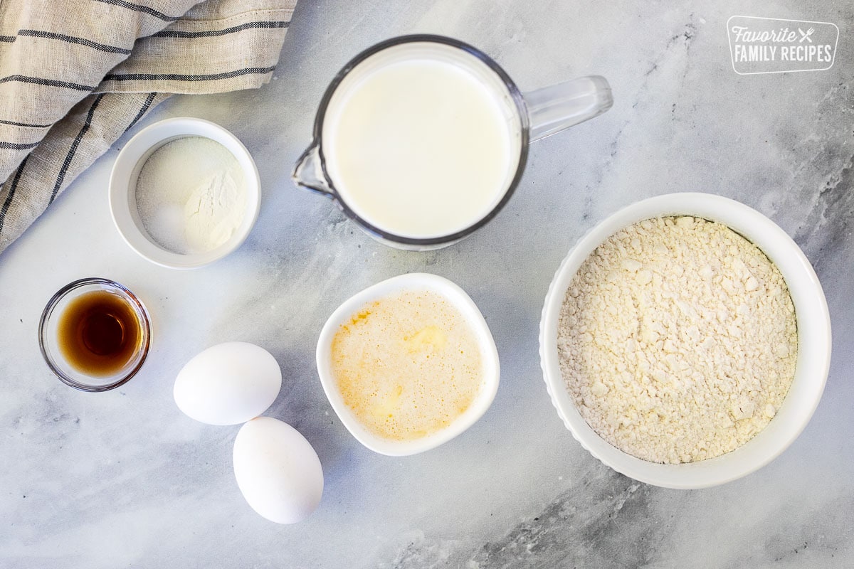 Ingredients to make homemade waffles, including flour, milk, melted, butter, eggs, vanilla, sugar, baking powder and salt.