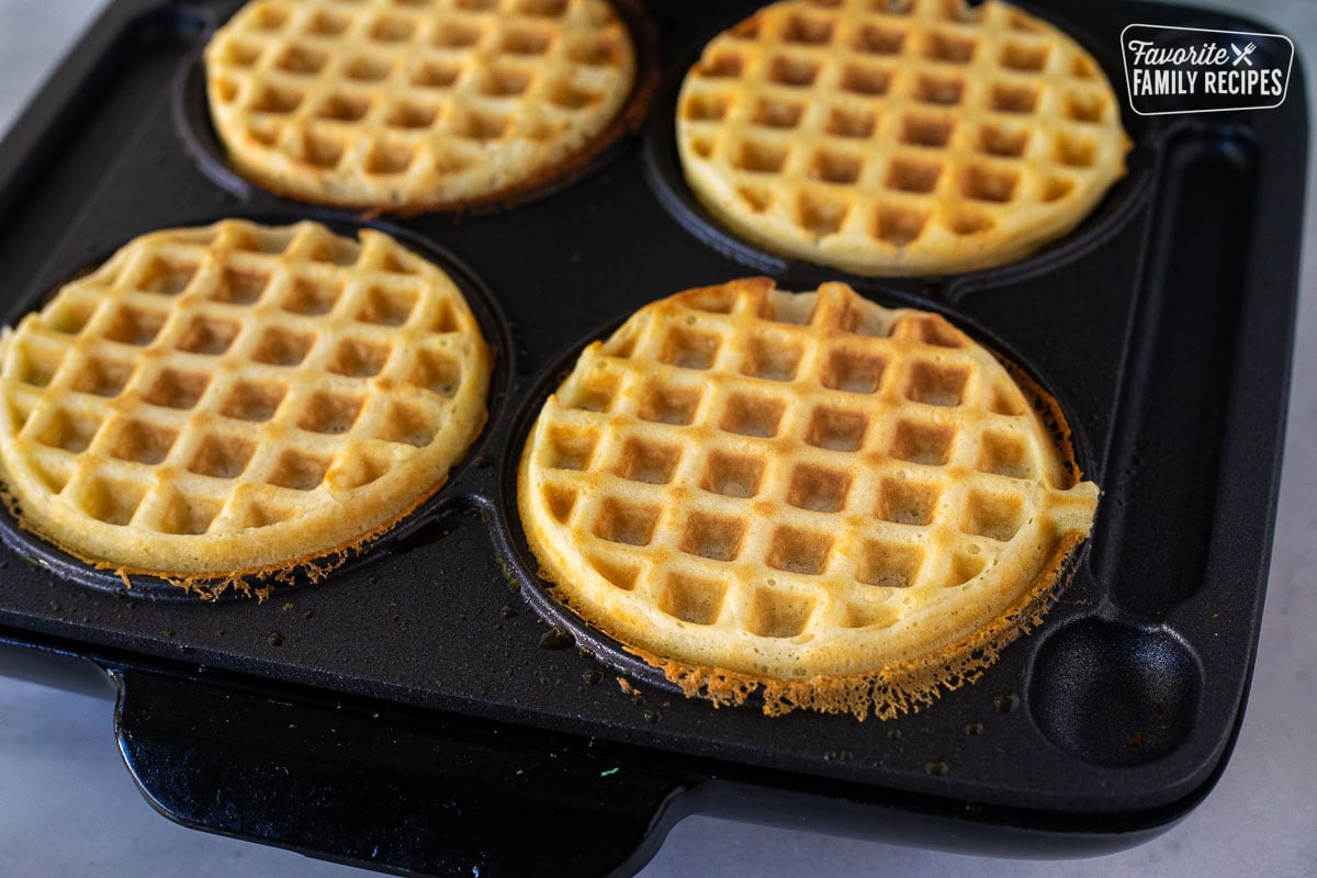 Golden waffles in a waffle iron.