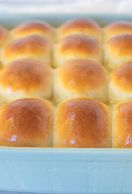 Baking dish of baked homemade dinner rolls with melted butter brushed on top.