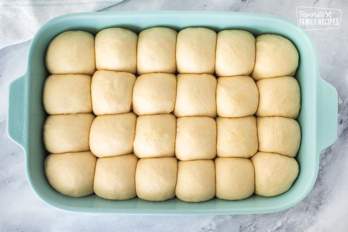 Glass baking dish with dough balls risen.