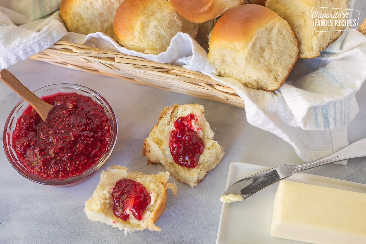 Homemade dinner roll split into with butter and jam spread on top.