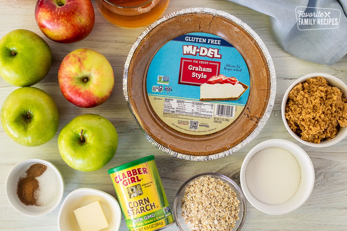 Ingredients for Gluten Free Apple Pie including graham style gluten free crust, apple juice, apples, spices, butter, corn starch, oatmeal, sugar and brown sugar.