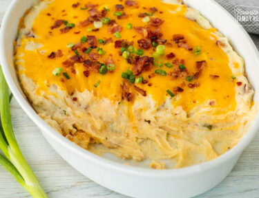 Casserole dish with scooped out areas from Loaded Mashed Potatoes.