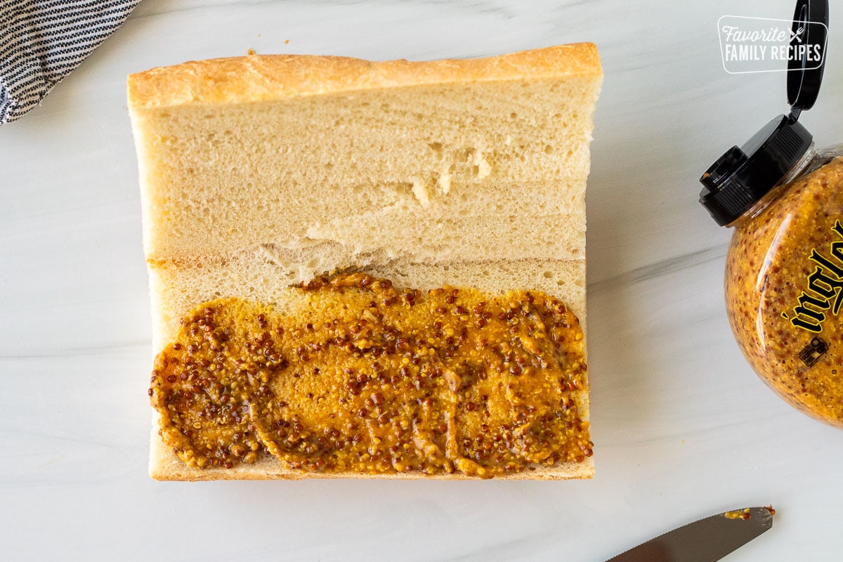 Stone ground mustard spread on a slice of French bread cut in half.