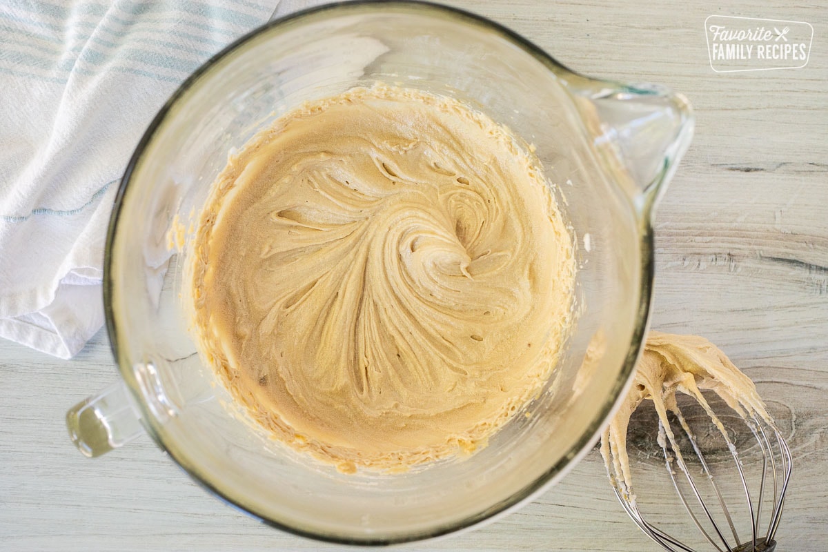 Mixing bowl of cake batter base with whisk attachment on the side.