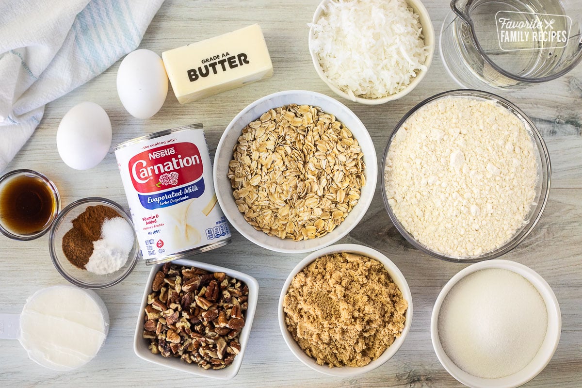 Ingredients to make Oatmeal Cake including oatmeal, flour, oatmeal, brown sugar, sugar, pecans, evaporated milk, coconut, butter, eggs, cinnamon, baking powder, salt, nutmeg, vanilla and shortening.