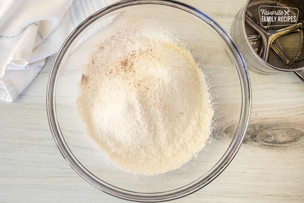 Glass bowl of sifted dry ingredients. Sifter on the side.