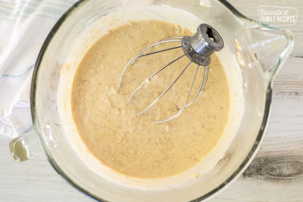 Glass mixing bowl with oatmeal and cake base. Whisk attachment resting in the mixing bowl.