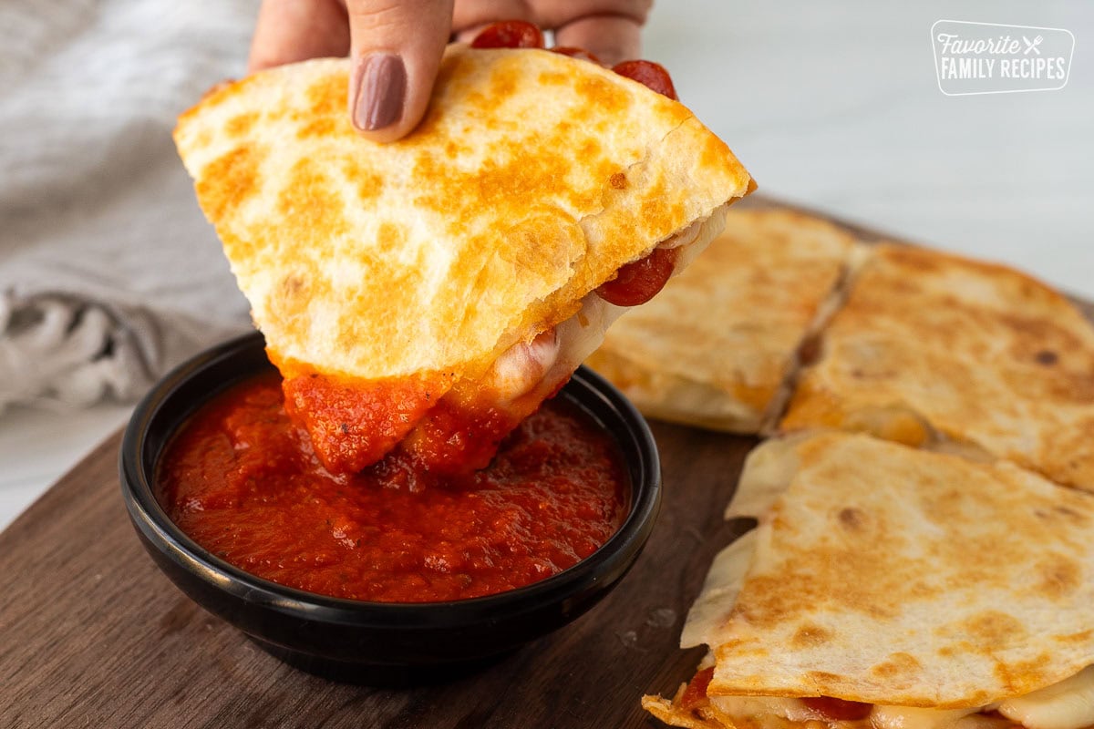 A pizzadilla dipped in pizza sauce for a kid-friendly snack.