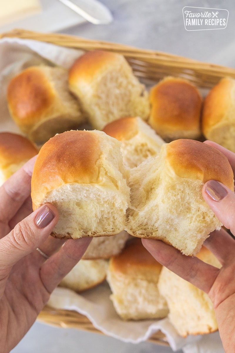 Hands pulling apart two dinner rolls.