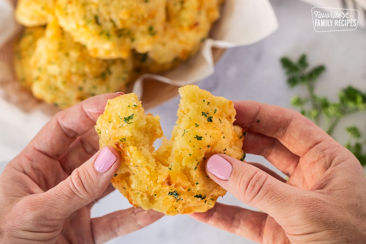 Hand pulling apart a Cheddar Bay Biscuit.