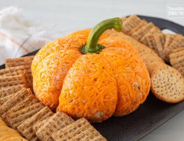 Pumpkin shaped cheese ball on a platter with crackers.