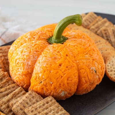 Pumpkin shaped cheese ball on a platter with crackers.