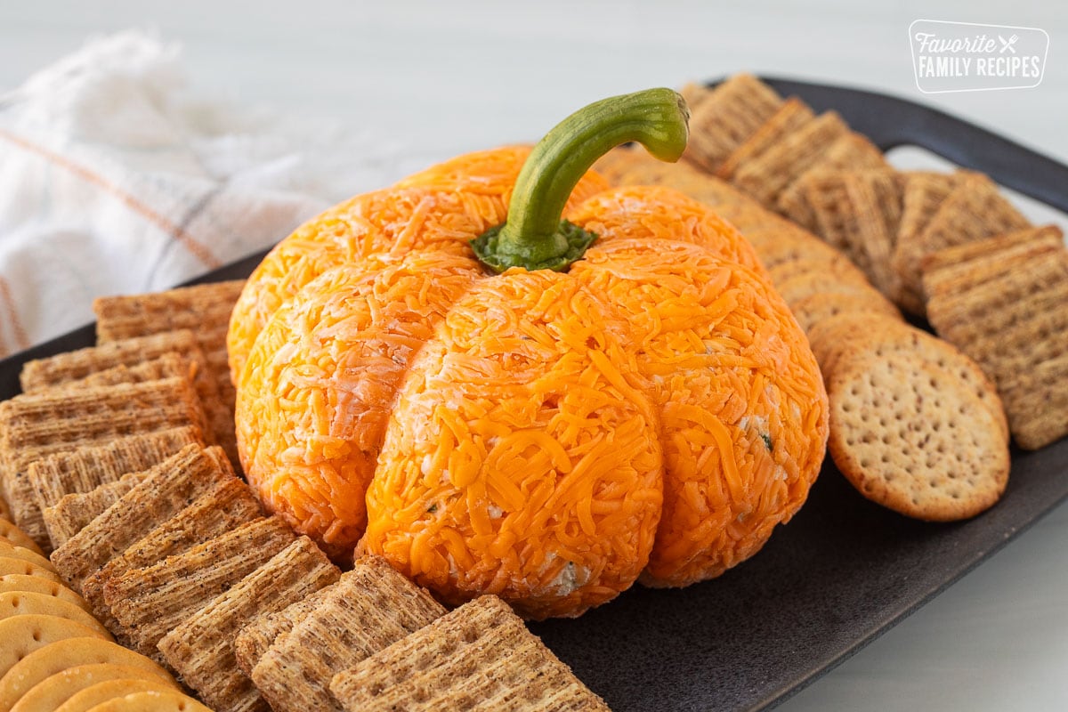 Pumpkin shaped cheese ball on a platter with crackers.